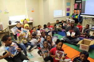 Students in a Philadelphia classroom smile and hold up their new Book Trust books.